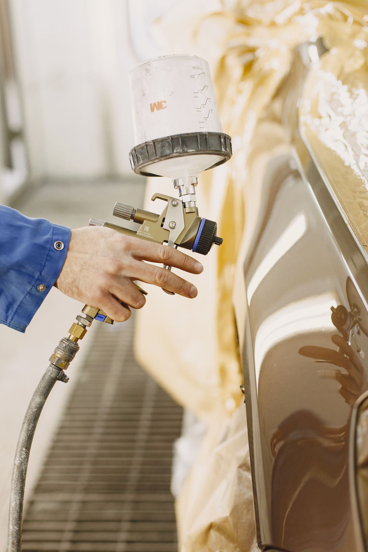 Paint spray tool applying finish to a vehicle panel